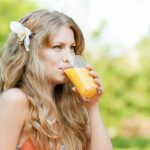 femeie care bea suc de portocale ce contine vitamine benefice pentru par vitaminaC fier