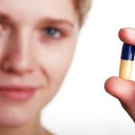 femeie care consuma capsule cu vitamine antioxidante sintetice