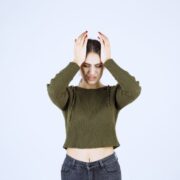 pretty young woman holding her face white wall