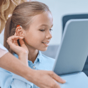 girl trying hearing aid front mirror