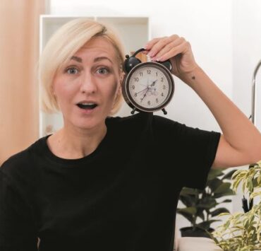 Postul intermitent susține longevitatea și sănătatea hormonală 7 excited beautiful blonde russian woman sits armchair holding alarm clock close face looking camera inside living room