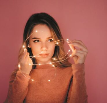 woman playing with garland pink background