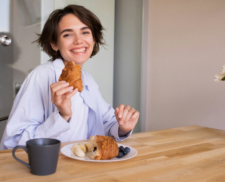 concept echilibru alimentar femeie mananca croissant fructe cafea mic dejun S3JmcKBSq5s